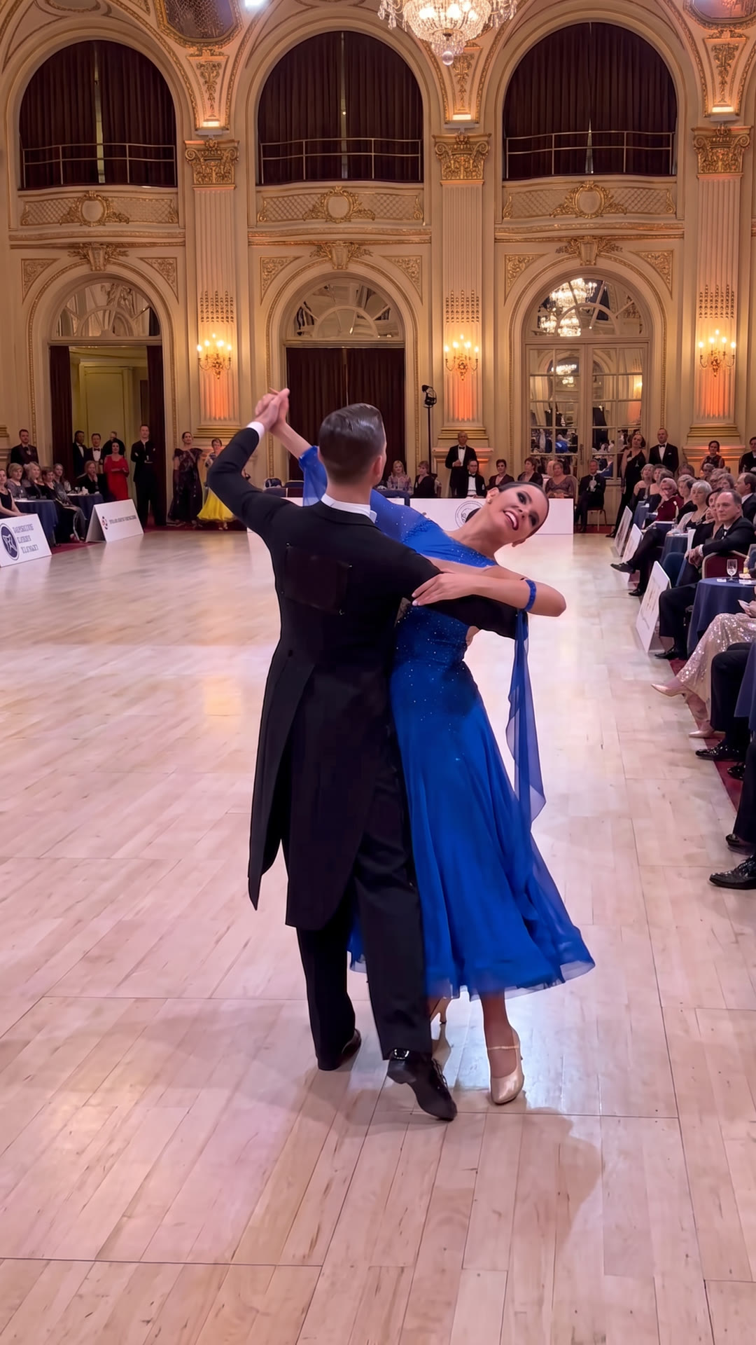 Ballroom couple dancing a Foxtrot feather step in a grand ballroom